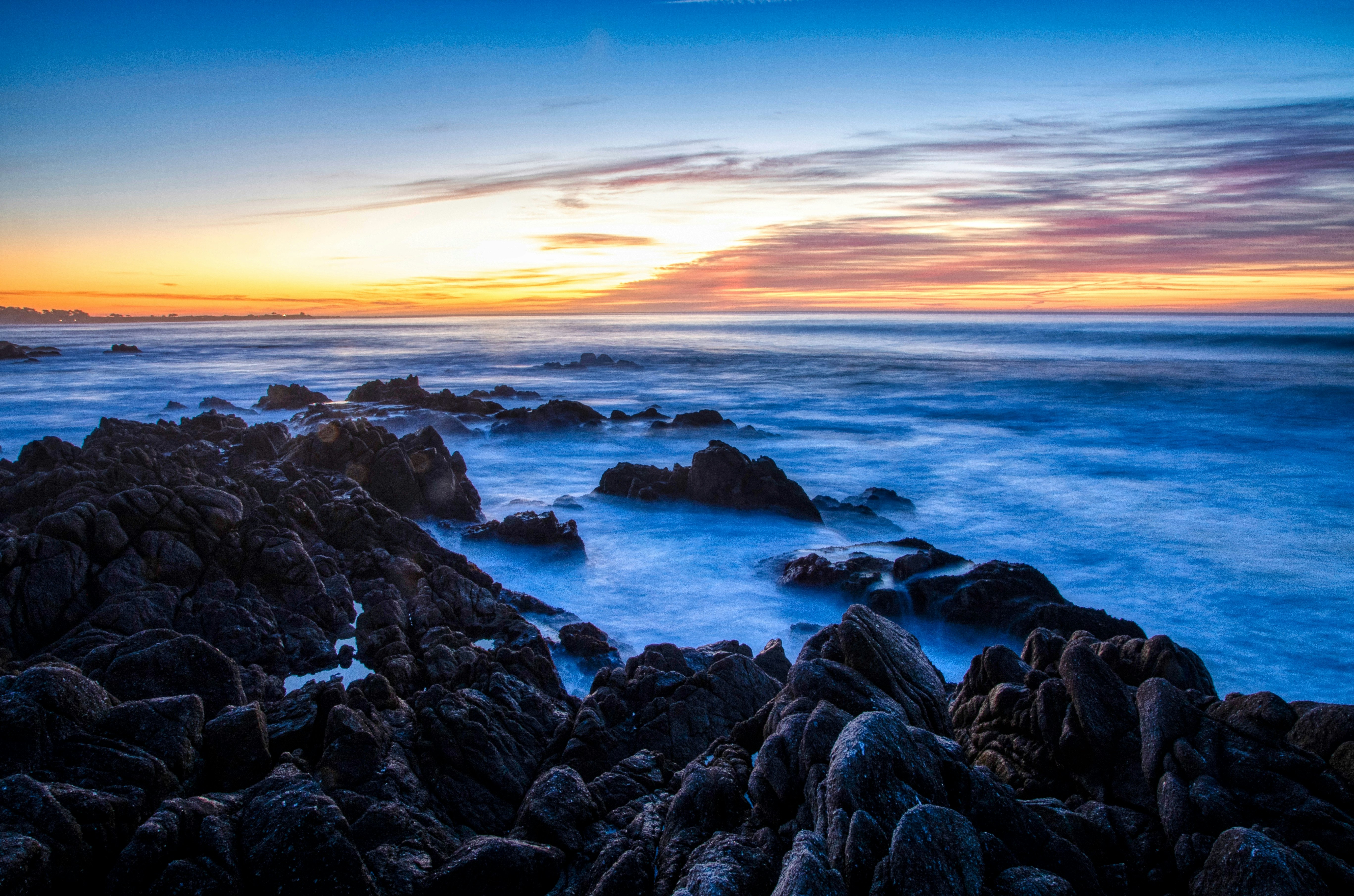 black rocks on sea shore during sunset